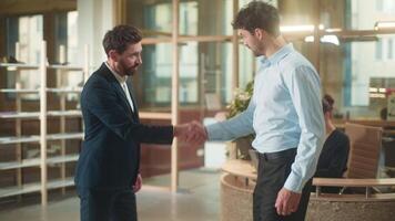 Two Caucasian men meeting in office handshaking business partners guys greeting hello gesture handshake smiling glad businessmen colleagues male teamwork deal partnership shaking hands client welcome video
