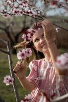 A joyful child in pink dances through an orchard of blooming almond trees, her laughter echoing in the spring air. photo