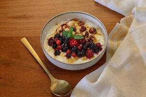 A delicious breakfast bowl with yogurt, mixed berries, nuts, and honey, placed on a table with a spoon and napkin. photo