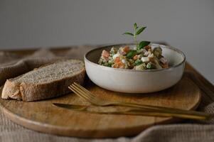 A rich and creamy Olivier salad with a rustic slice of dark bread, captured in a minimalist food photo. photo