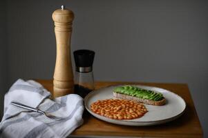A well-balanced breakfast plate with a crispy toast spread with avocado, hearty white beans, and a sunny-side-up egg photo