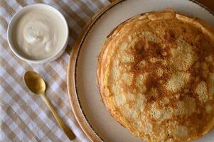 Homemade crepes with sour cream and berries. Delicate crepes folded with sour cream and topped with fresh berries. photo