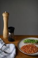 A wholesome morning meal with a crispy toast topped with avocado and black salt, served alongside white beans in red sauce and a fried egg. photo