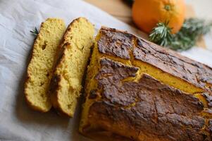 A freshly baked orange cake with a golden crust sits on a rustic wooden table, its moist and fluffy interior revealed in a neatly sliced piece, dusted with powdered sugar. photo