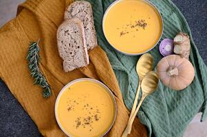 A steaming bowl of creamy pumpkin soup with rustic sourdough, perfect for autumn. photo