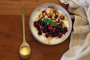 A creamy yogurt bowl with blueberries, raspberries, almonds, and a honey drizzle, styled with a spoon and towel. photo