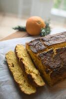A homemade orange cake, with caramelized edges and a soft, fragrant center, is elegantly presented on a rustic wooden board, ready to be savored photo