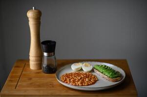 A rustic yet sophisticated morning meal with homemade white beans, a fried egg, and avocado toast seasoned with black salt. photo