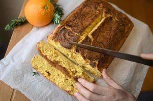 A rustic orange cake, adorned with thinly sliced candied oranges, is artfully arranged on a wooden table, exuding warmth and nostalgia. photo