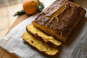 A slice of moist orange cake, rich with citrus zest, sits on a vintage napkin, its airy texture complemented by a dusting of powdered sugar. photo