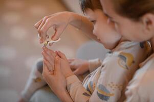A mother carefully trims her childs fingernails with child-safe manicure scissors. photo