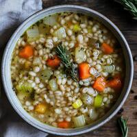 Steaming barley soup garnished with fresh rosemary in bowl photo
