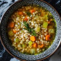 Steaming pearl barley soup garnished with fresh herbs and vegetables photo