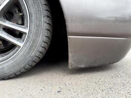 Close up photo of car front bumper clearance, very low suspension on vehicle with cool style. Modified car with bottom down on asphalt for cool look. Lowered car culture. Car is lying on the ground