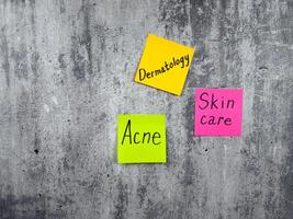 Dermatology concept with conceptual peeled background resembling rough skin. The importance of taking care of your body and removing acne. Words on sticky notes with skin health theme photo