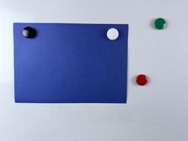 Blue note paper attached to whiteboard with colorful magnets perfect for reminders presentations and creative workspaces useful in both office and educational settings photo