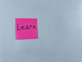 Sticky note with the word Learn written on it, pinned on white background. Photo symbolizes education, knowledge, and growth. Perfect for illustrating concepts of learning and personal development
