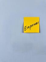 Sticky note with Empower written on it, affixed to a white background. This image represents strength and confidence, ideal for themes of empowerment and personal growth photo
