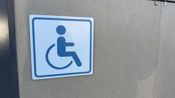 Blue sign of disabled person in wheelchair on wall of building. Concept of creating accessible areas. Mobility defects of person in wheelchair and protection rights of people with disabilities photo