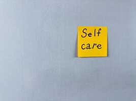 Sticky note with the words Self Care written on it, placed on white background. Ideal for illustrating themes of well being, health, and self love. Great for concept creation photo