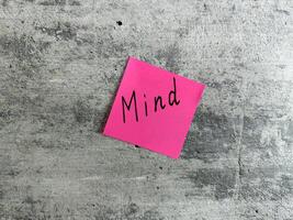 Vibrant pink sticky note with the word Mind displayed on a textured grey background, representing concepts of mental awareness, mindfulness, and personal reflection for growth and understanding photo