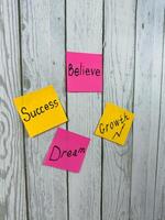 Set of colorful sticky notes with words on white wooden board. Photo is ideal for emphasizing themes of inspiration, motivation, and achieving personal goals