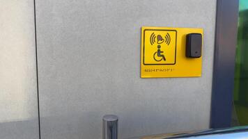 Disabled person sign with braille text and panel with button to call staff for assistance at entrance to building. Social problem of creating accessible areas for people with disabilities photo
