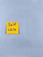 Sticky note with Self Care written on it, affixed to white background. This image represents well being and self love, ideal for themes of personal wellness and self care photo