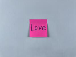 Sticky note with the word Love written on it, pinned on white background. Image represents affection, connection, and care. Ideal for illustrating concepts of love and relationships photo