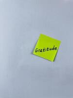 Sticky note with the word Gratitude written on it, placed on white background. Ideal for illustrating themes of thankfulness, appreciation, and positivity. Great for concept creation photo