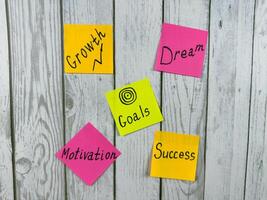 Collection of colorful sticky notes with Motivation, and Success words placed on white wooden background. Photography represents concepts of motivation and inspiration for personal achievement photo
