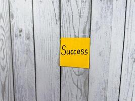 Sticky note featuring the word Success set against a textured wooden background, representing the essence of achievement, personal growth, and the pursuit of meaningful goals photo