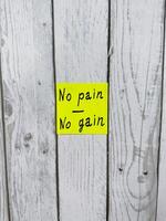 Yellow sticky note with the phrase No pain No gain written on it, placed on white background. Perfect for themes of motivation and achieving goals. Suitable for concept illustrations photo