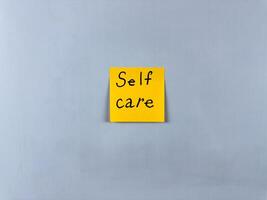 Sticky note with the words Self Care written on it, pinned on white background. Photo symbolizes well being, self love, and health. Perfect for illustrating concepts of self care and personal wellness