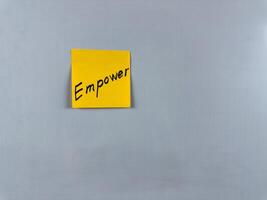 Sticky note with the word Empower written on it, placed on a white background. Ideal for illustrating themes of strength, confidence, and motivation. Great for concept creation photo
