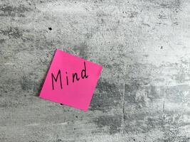 Bright pink sticky note featuring the word Mind placed on a textured grey background, symbolizing concepts of mindfulness, awareness, and mental clarity for personal growth and inspiration photo
