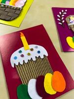 Whimsical handmade Easter card features decorated cake with candle, complemented by colorful felt eggs. Perfect for adding joyful touch to Easter celebrations and sending heartfelt wishes photo