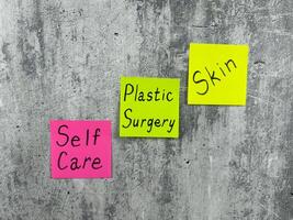 Bright sticky notes with words about taking care of your health. Important reminder on shabby background with words about plastic surgery and skin care photo