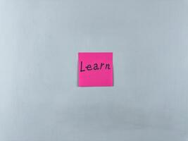 Sticky note on white background with word Learn. Concept of continuous learning and personal development. Development and acquisition of new information through learning photo