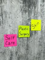 Vertical photo of sticky notes with words reminding about skin care. Use plastic surgery for health and skin improvement. Simple concept of selfcare