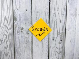 Bright sticky note displaying the word Growth, placed on textured wooden background, symbolizing personal development and progress in life photo