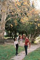 Mom and dad are standing on the path in the park, holding their little daughter in their arms raised photo
