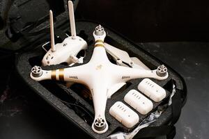USA, Arizona - March 10, 2025. White DJI Phantom 3 drone with spare batteries and a control panel lies in a protective case on a black table photo