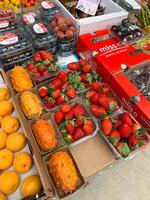 Budva, Montenegro - 25 december 2022. Fresh strawberries, kiwanos, peaches lie in boxes on the counter of the store photo