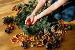 Designer is arranging the Christmas wreath while sitting on the floor. Cropped. Faceless photo