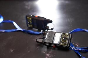 USA, Arizona - March 10, 2025. Pair of small Baofeng BF-T1 walkie-talkies lie on a black table with blue ribbons photo