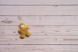 Gingerbread man in a mask lies on the edge on a light wooden background photo