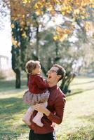 Laughing dad holding in his arms a laughing little girl in the park photo