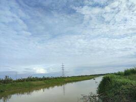 a river with a bridge and power lines in the background photo