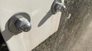 Metal bolts fastening a panel to a concrete surface under bright sunlight in an industrial setting photo